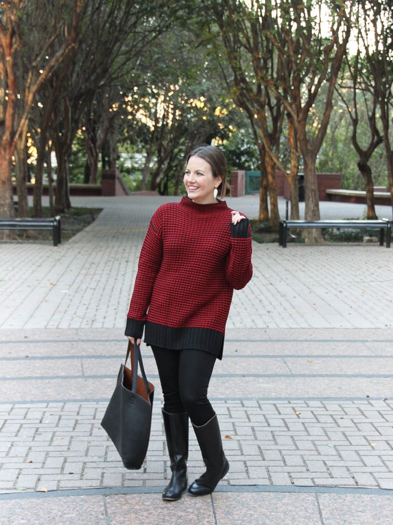 Houston Fashion Blogger styles a winter outfit idea featuring a red long sweater with black skinny jeans and riding boots.