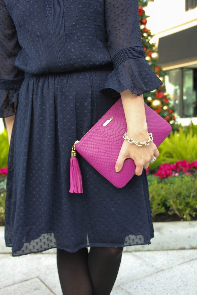 Houston Fashion blogger styles a holiday party outfit in a navy dress and pink clutch.