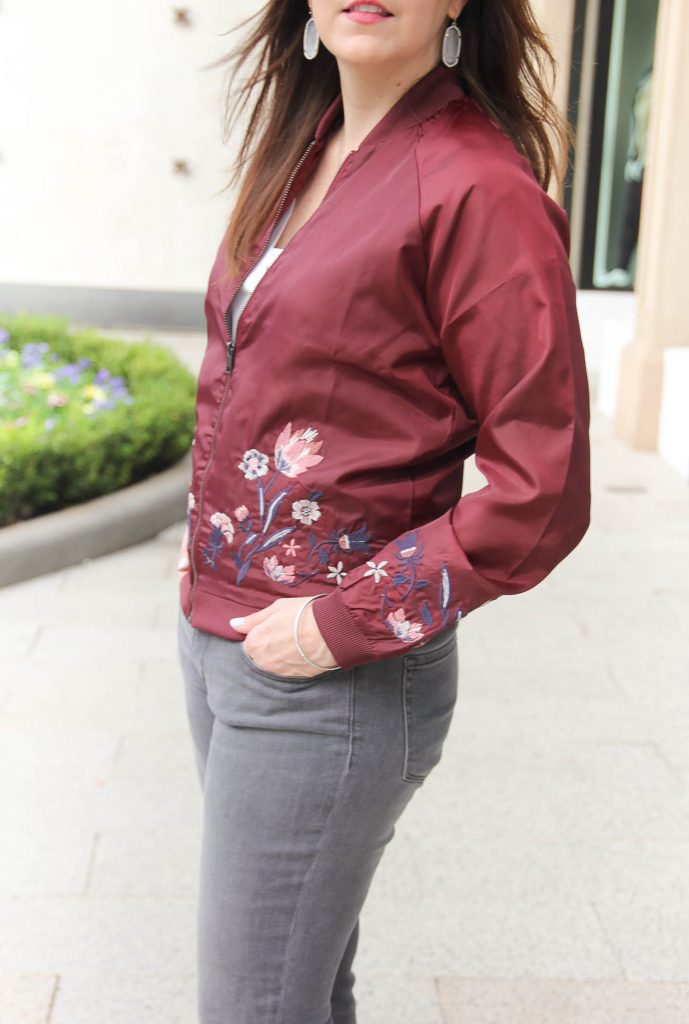 Houston Style Blogger Karen Rock of Lady in Violet wears an embroidered floral bomber jacket from nordstrom with gray skinny jeans and kendra scott elle earrings.