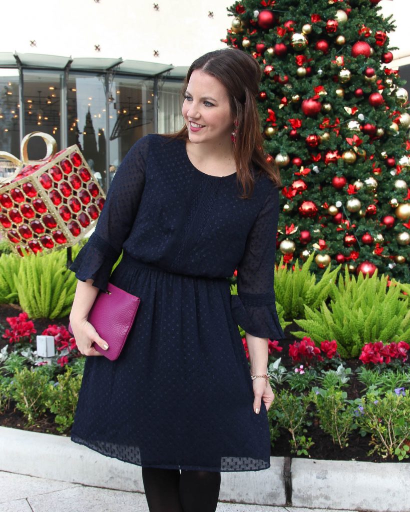 Karen Rock, a Houston Fashion Blogger wears a modest holiday dress idea featuring a navy banana republic dress with black tights and a pink clutch.