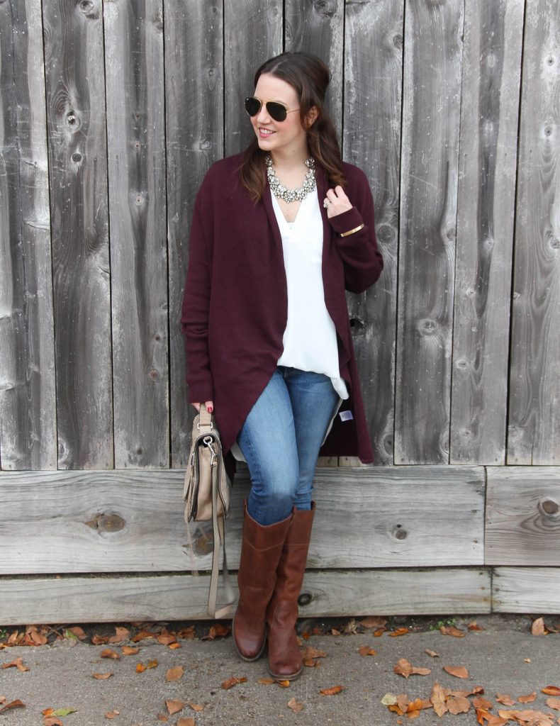 Houston Fashion Blogger Lady in Violet styles a warm winter outfit with a burgundy long cardigan, a white tunic blouse, blue jeans, and brown boots.