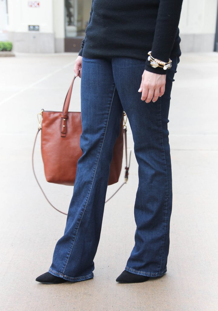 Lady in Violet, a Houston style blogger wears a casual Friday office outfit with flared jeans and a black sweater.