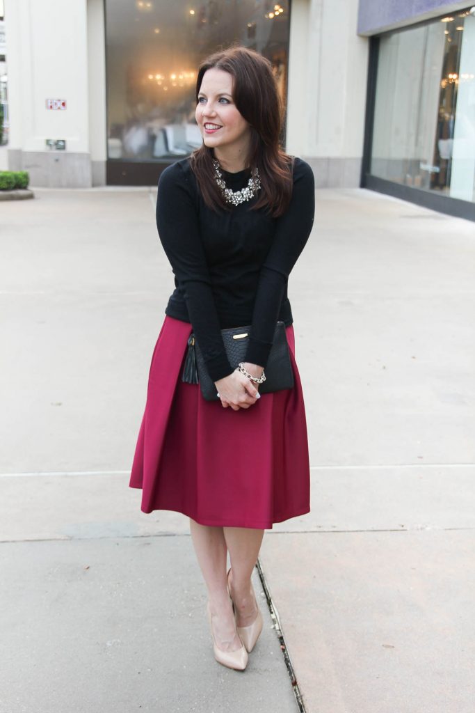 Lady in Violet, a Houston Fashion Blogger wears a winter office outfit including a pink midi skirt and black crewneck sweater.