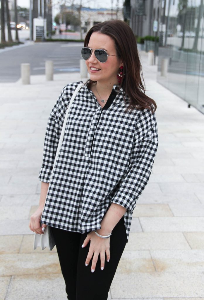 Houston style blogger styles a spring outfit including a gingham plaid top with jeans and pink earrings.