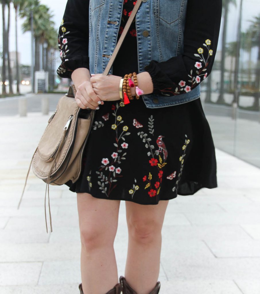 Houston Fashion Blogger styles a rodeo outfit including beaded tassel bracelets, an embroidered dress, and saddle bag.