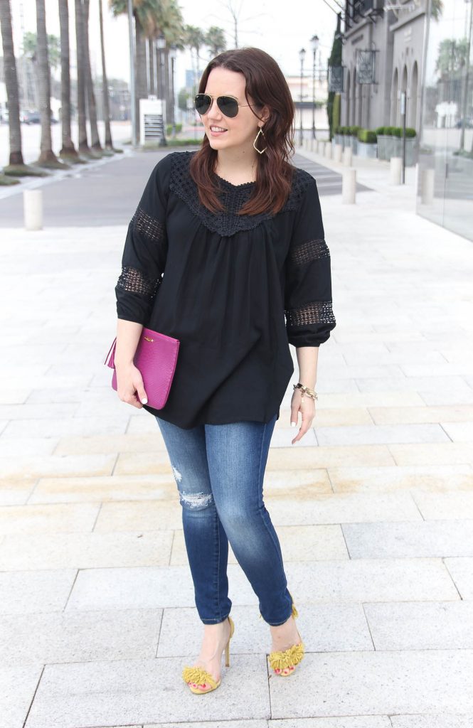 Houston Fashion Blogger styles spring outfit featuring black crochet top with distressed jeans and yellow fringe heels.