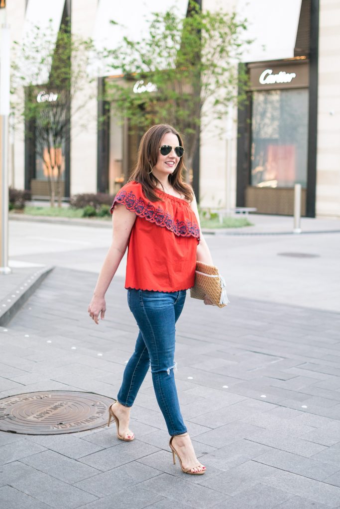 Houston fashion blogger styles a spring outfit idea including a red one shoulder top with distressed jeans and heels.