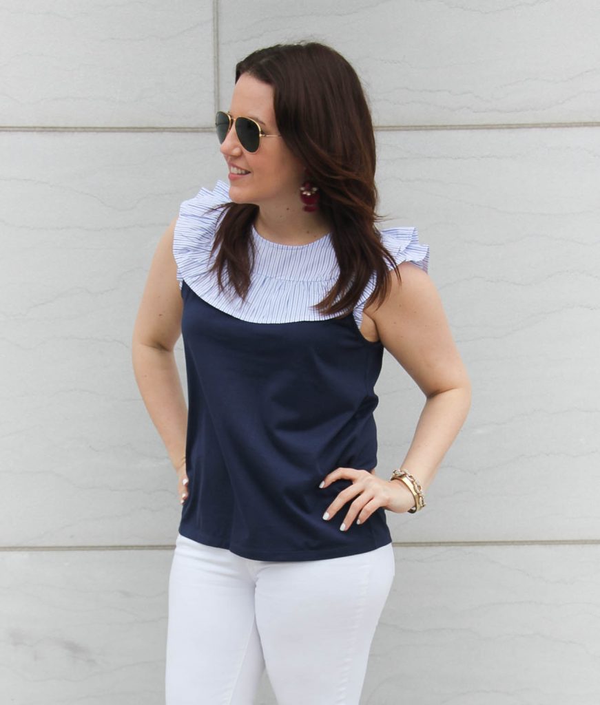 Lady in Violet wears a navy ruffle bib sleeveless tee with white jeans.