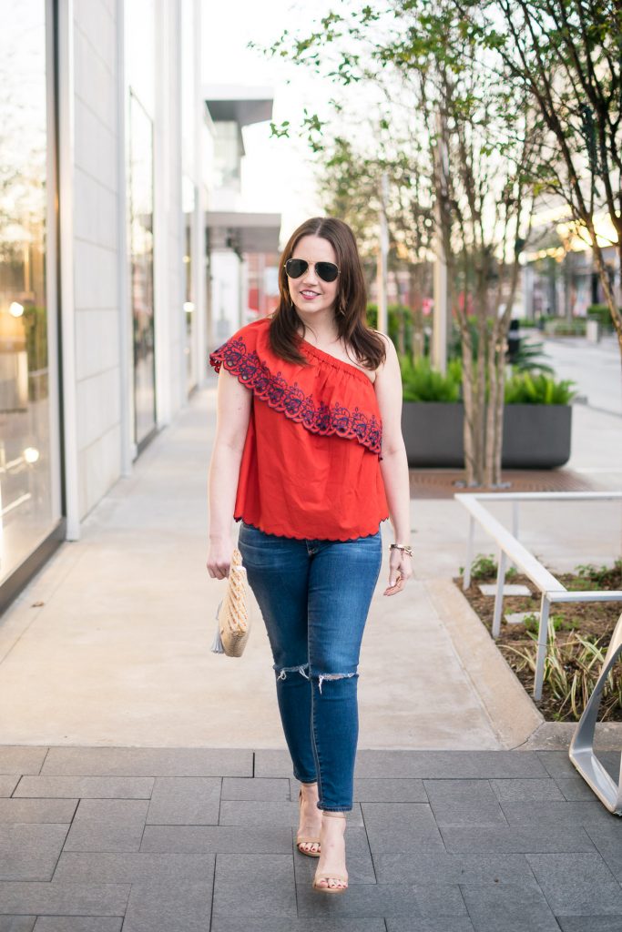 Lady in Violet wears a spring casual weekend outfit with heels, jeans, and a one shoulder top.