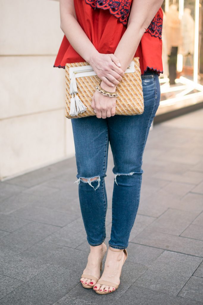 Lady in Violet, a Houston based fashion blogger, carries a cute spring clutch with white tassels and wears ag distressed jeans and steve madden stecy sandals.