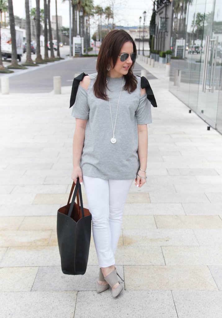 Karen Rock, a Houston fashion blogger wears a spring weekend outfit idea including gray bow shoulder tee, white jeans, and gray heels.