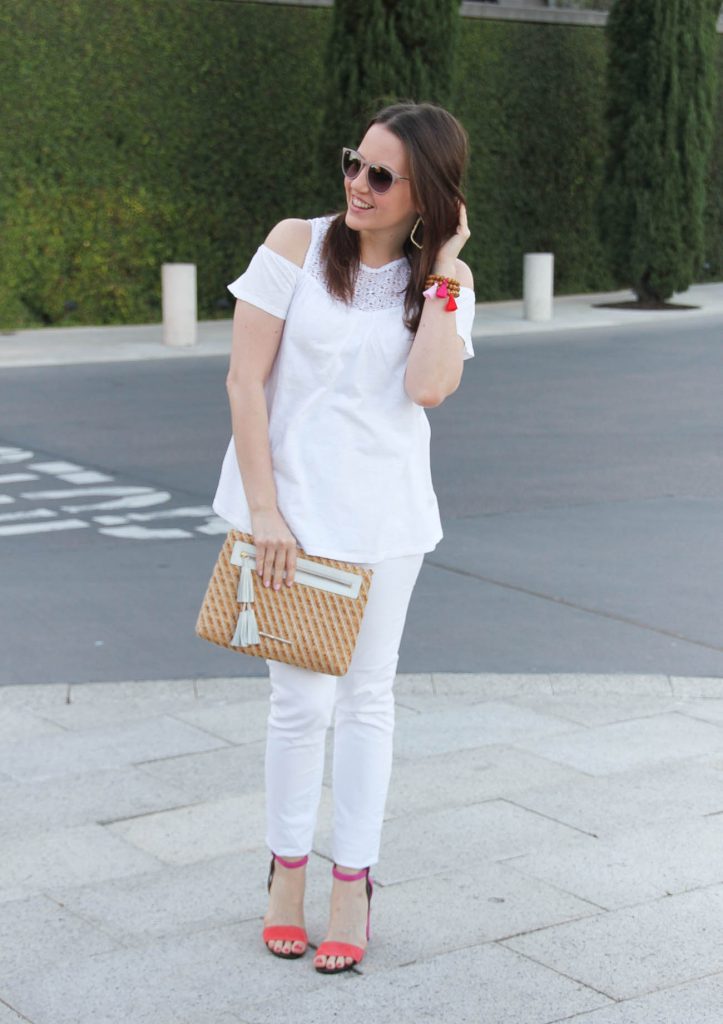 Karen Rock, a Houston fashion blogger, styles a spring outfit including a white cold shoulder top with white jeans and pink block heel sandals.