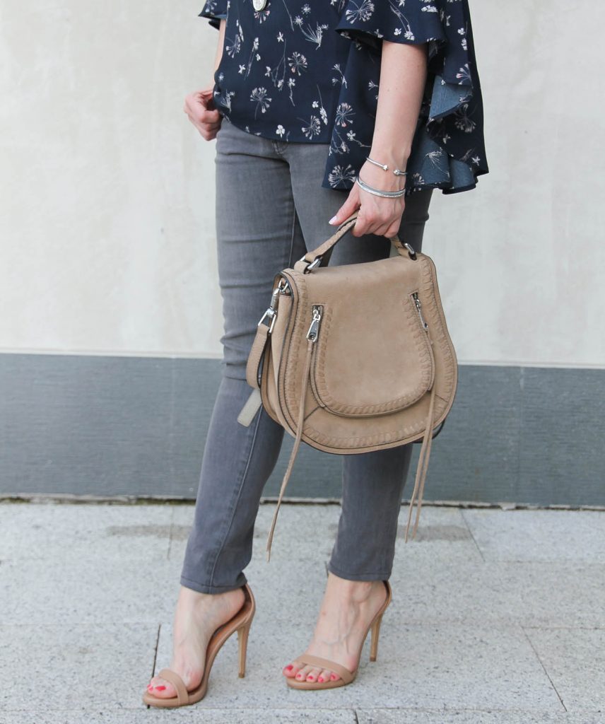 Houston fashion blogger Lady in Violet carries the Rebecca Minkoff vanity saddle bag and wears gray skinny jeans and Steve madden Stecy sandals.