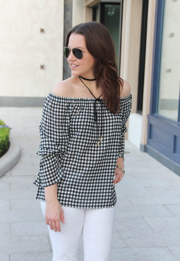 Lady in Violet, a Houston fashion blogger, wears a dressy casual outfit idea including a gingham off the shoulder top with a choker necklace and white jeans.