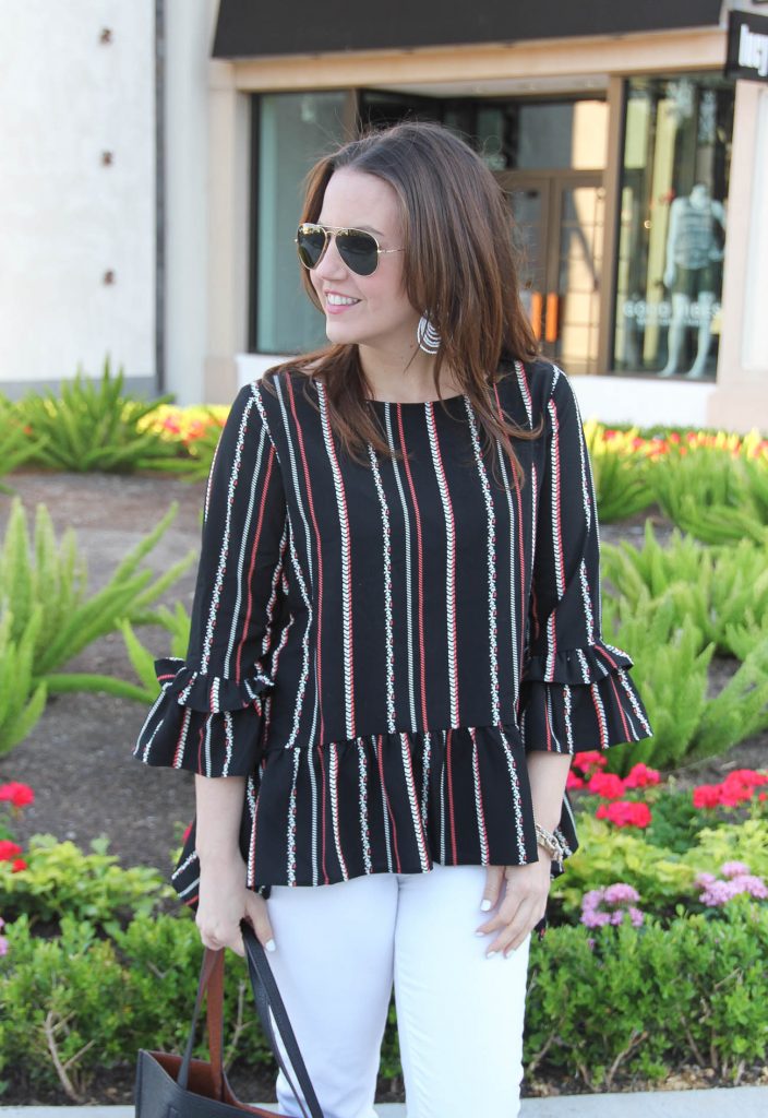 Houston style blogger Karen Rock wears spring outfit including bell sleeve top, white statement earrings, and white jeans.